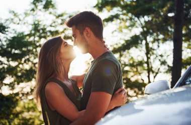 Beyaz arabanın ön tarafında. Genç ve güzel bir çift gündüz vakti ormanda iyi vakit geçirir..