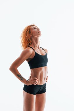 Kızıl saçlı kadın vücut geliştirici beyaz arka planda stüdyoda..