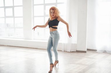 Güzel model. Çekici kızıl saçlı kadın pencerenin yanındaki uzay odasında poz veriyor..