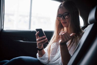 Zeki iş kadını, siyah iç mekanı olan lüks arabanın arka koltuğunda oturur..