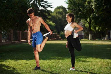 Bacaklar için egzersiz. Erkek ve kadının şehirde gündüz vakti parkta fitness günü var..