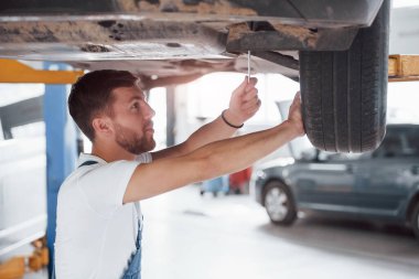 Araba sallanıyor. Mavi üniformalı işçi otomobil salonunda çalışıyor..