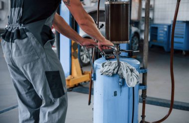 Araba yenileme teknolojisi. Erkek tamirci garajdaki bozuk otomobili tamir etmek için özel bir cihaz kullanıyor..