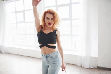 Aktif kadın dansçı. Çekici kızıl saçlı kadın pencerenin yanındaki uzay odasında poz veriyor..