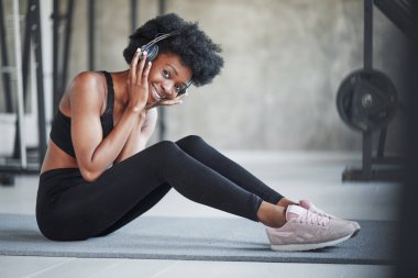 Kıvırcık saçlı ve spor elbiseli Afrikalı Amerikalı kadın spor salonunda spor yapıyor..