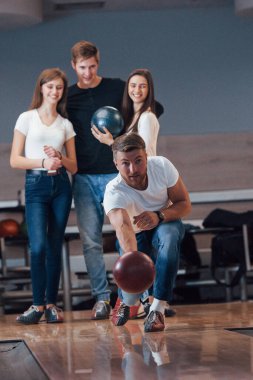Dikey fotoğraf. Genç neşeli arkadaşlar hafta sonları bowling kulübünde eğleniyorlar..