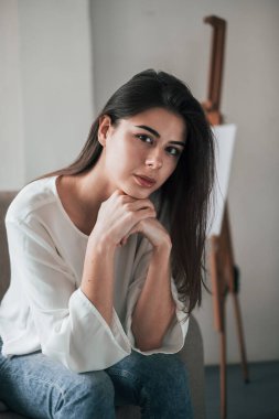 İşten sonra sanat stüdyosunda. Güzel bir portre. Beyaz duvarları ve pencereden gelen gün ışığıyla odada genç bir esmer..