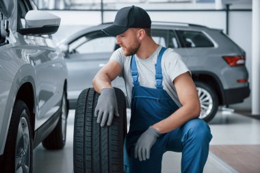 Mola verdim. Tamirhanede lastik tutan bir tamirci. Kış ve yaz lastiklerinin değiştirilmesi.