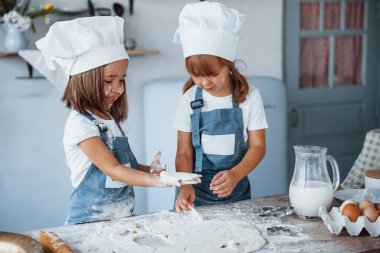 Yemek pişirmeye odaklan. Beyaz şef üniformalı aile çocukları mutfakta yemek hazırlıyorlar..