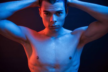 İnsan vücudu. Stüdyo karanlık stüdyoda neon ışıkla çekiliyor. Ciddi bir adamın portresi..