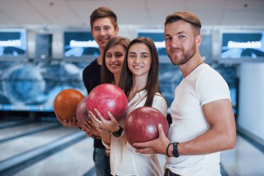 Yan görüş. Genç neşeli arkadaşlar hafta sonları bowling kulübünde eğleniyorlar..
