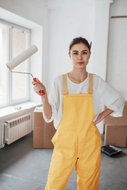 Beyaz üniformalı ve elinde bir aletle. Beyaz duvarları ve pencereden gelen gün ışığıyla odada genç bir esmer..