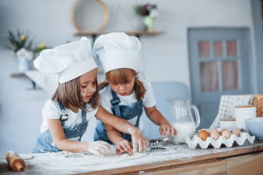 Yemek pişirmeye odaklan. Beyaz şef üniformalı aile çocukları mutfakta yemek hazırlıyorlar..