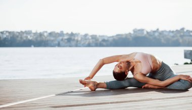 Yıllarca süren eğitimin sonuçları. İnce vücutlu genç bir kadın göle karşı egzersiz yapıyor..