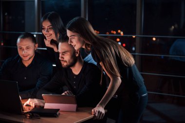 Laptoptan çıkan hafif ışıklandırma. Genç iş adamlarından oluşan bir ekip gece ofiste projeleri üzerinde çalışıyor..