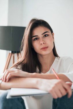 Strabismus bozukluğu bu kızı daha az güzel yapmaz. Beyaz duvarları ve pencereden gelen gün ışığıyla odada genç bir esmer..