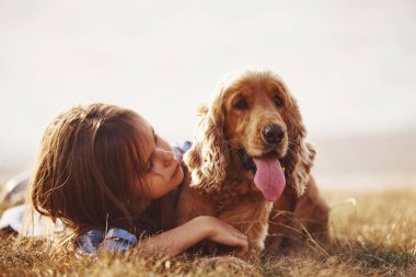 Hayvan ve insanın güzel dostluğunun ön görüntüsü. Şirin küçük kız, güneşli bir günde köpeğiyle dışarı çıkar..