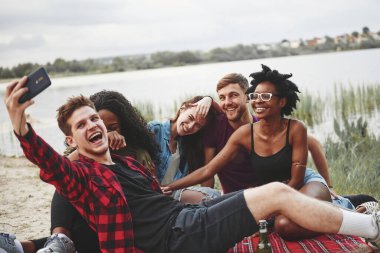 Kameraya gülümse. Bir grup insan sahilde piknik yapıyor. Arkadaşlar hafta sonu eğlenir..