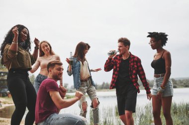 Birlikte dans etmek. Bir grup insan sahilde piknik yapıyor. Arkadaşlar hafta sonu eğlenir..