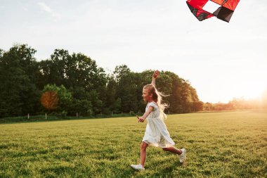 Burası sıcak, ama rüzgar tazelenmeye yardımcı oluyor. Beyaz elbiseli mutlu kız sahada uçurtmayla eğleniyor. Güzel doğa..