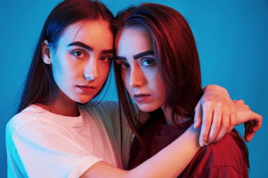Birbirlerini seviyorlar. Stüdyo içeride neon ışıkla çekiliyor. İki güzel ikizin fotoğrafı..