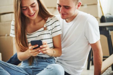 Telefonla. Yeni dairelerinde neşeli genç bir çift. Taşınma kavramı.