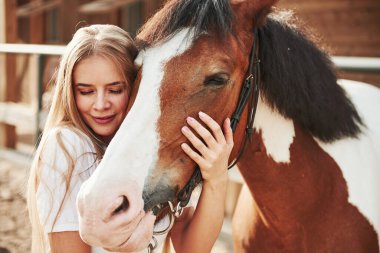 Atını kucaklıyor. Gündüz vakti çiftlikte mutlu bir kadın.