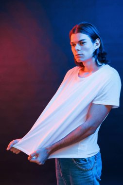 Günlük kıyafetlerle. Stüdyo karanlık stüdyoda neon ışıkla çekiliyor. Ciddi bir adamın portresi..