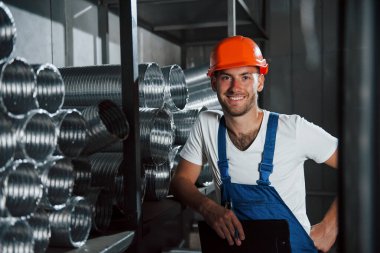 Samimi bir gülümseme. Üniformalı adam prodüksiyonda çalışıyor. Endüstriyel modern teknoloji.