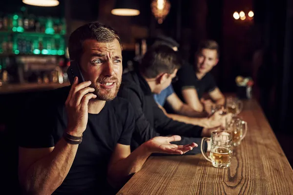 Άνθρωπος Μιλάει Στο Τηλέφωνο Τρεις Φίλαθλοι Ένα Μπαρ Βλέπουν Ποδόσφαιρο — Φωτογραφία Αρχείου