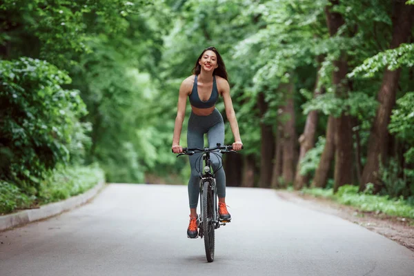 Ciclista Feminina Uma Bicicleta Estrada Asfalto Floresta Dia Ensolarado — Fotografia de Stock