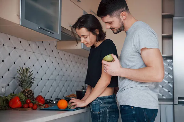 男はガールフレンドの後ろに立っている 若いですカップルで現代的なキッチンに自宅で週末時間で朝 — ストック写真