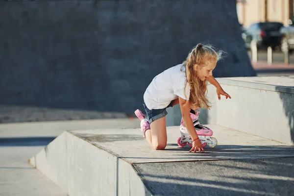 かわいいです女の子とともにローラースケート屋外で座っています極端なスポーツのためにランプ — ストック写真