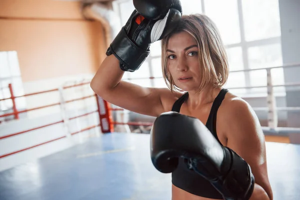 Wipes the sweat from the forehead. Female sportswoman in the boxing ring. In black colored clothes.