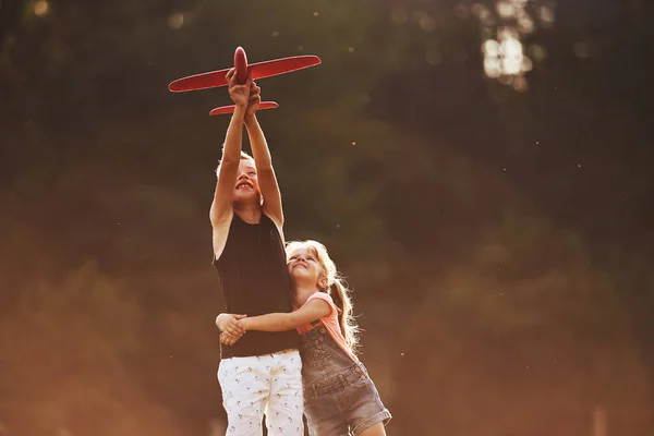 Kız Oğlan Ellerinde Kırmızı Oyuncak Uçakla Dışarıda Eğleniyorlar — Stok fotoğraf