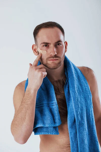 Negligent Shaving Plaster Face Man Blue Towel Stands White Background — Stock Photo, Image
