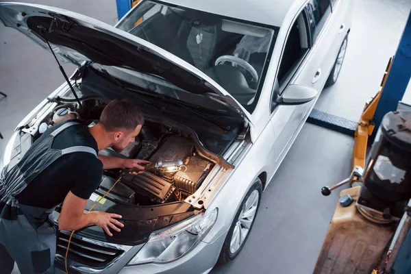 Uses Lighting Equipment Man Grey Uniform Repairs White Automobile Indoors — Stock Photo, Image