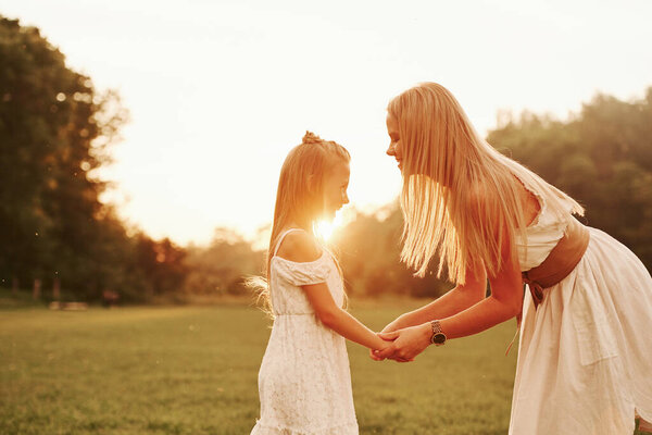 Having conversation. Mother and daughter enjoying weekend together by walking outdoors in the field. Beautiful nature.