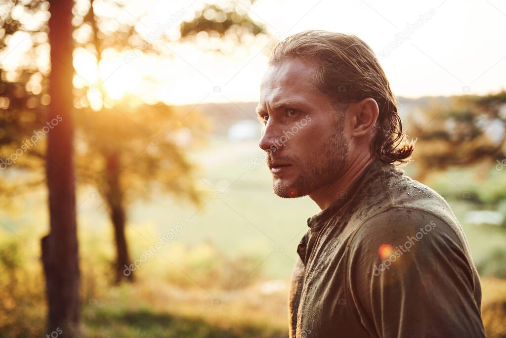 Beautiful man in the forest. Good weather. Beautiful orange colored sunlight.