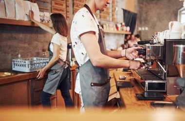 Makineyle. İki genç kafe çalışanı içeride. İş ve hizmet kavramı.