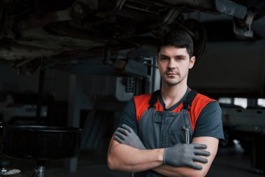 Atölyesinde elinde İngiliz anahtarıyla duran üniformalı ciddi bir işçinin portresi..