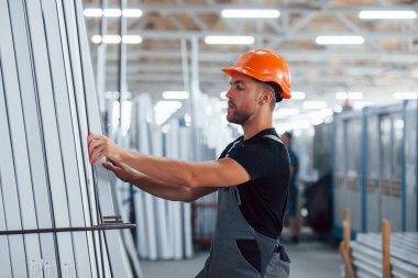 Depoda bir sürü nesneyle birlikte. Fabrikada sanayi işçisi. Turuncu şapkalı genç teknisyen..