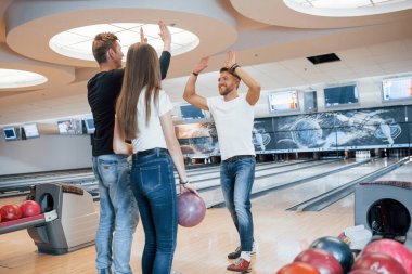 Çak bir beşlik. Genç neşeli arkadaşlar hafta sonları bowling kulübünde eğleniyorlar..