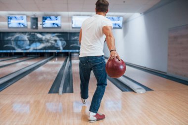 Sadece bir kişi. Kulüpte bowling oynayan günlük kıyafetli bir adam..