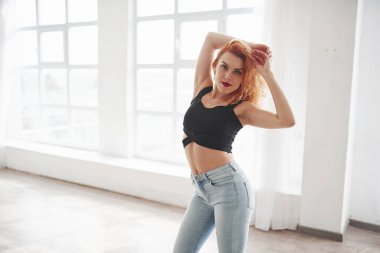 Basit ve lüks bir iç mekan. Çekici kızıl saçlı kadın pencerenin yanındaki uzay odasında poz veriyor..