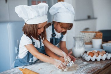 Yemek pişirmeye odaklan. Beyaz şef üniformalı aile çocukları mutfakta yemek hazırlıyorlar..