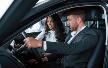 İlginç bir bakış. Otomobil kuaföründe yeni araba deneyen sevimli başarılı çift..