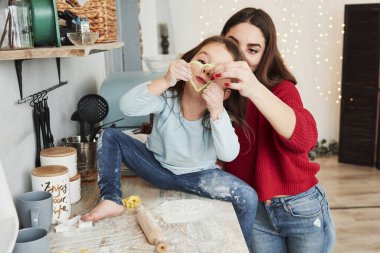Kurabiyeler için kalp şeklindeki yeşil formu gösteriyorum. Aile fotoğrafı. Anne ve kızı mutfakta biraz eğleniyor..