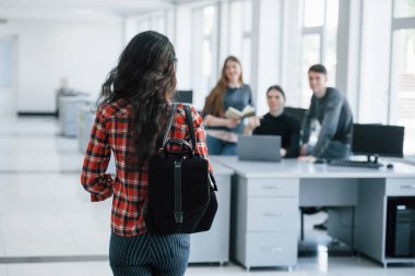 Arkadan bak. Modern ofiste çalışan günlük kıyafetli bir grup genç..