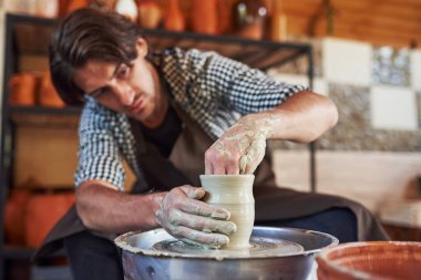 Seramikçi çömlekçi çarkı kullanır ve el yapımı kil ürünü üretir..